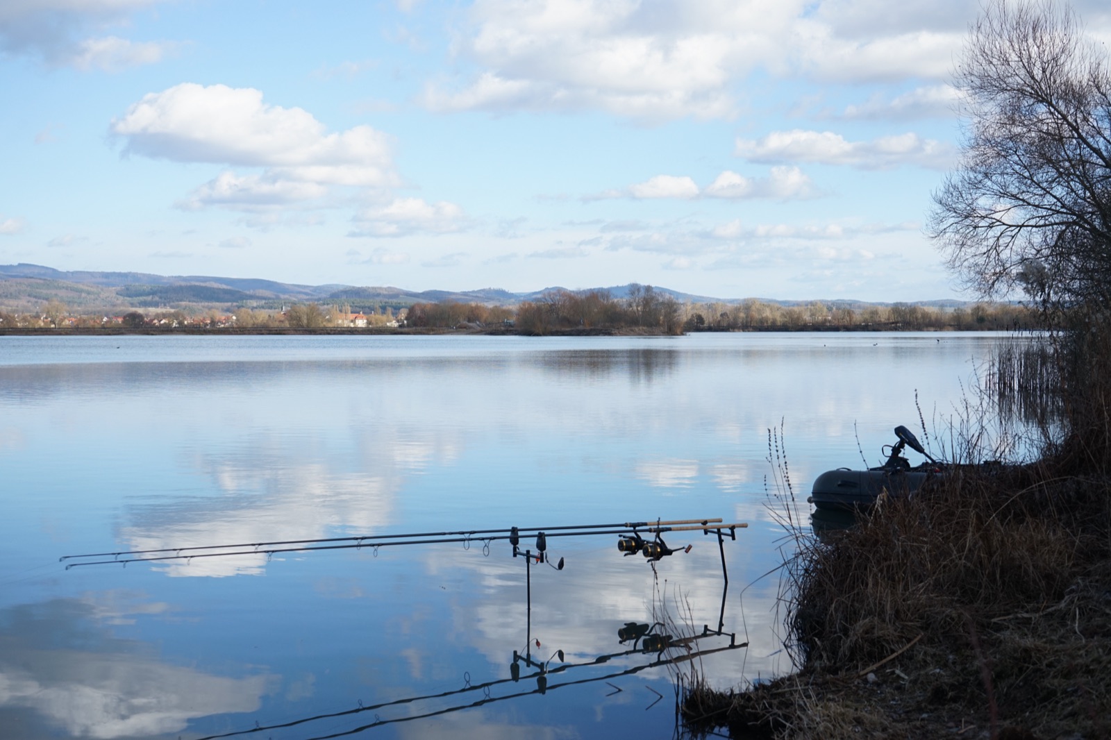 Rod Pod mit Ruten am ruhigen See, dahinter das Schlauchboot